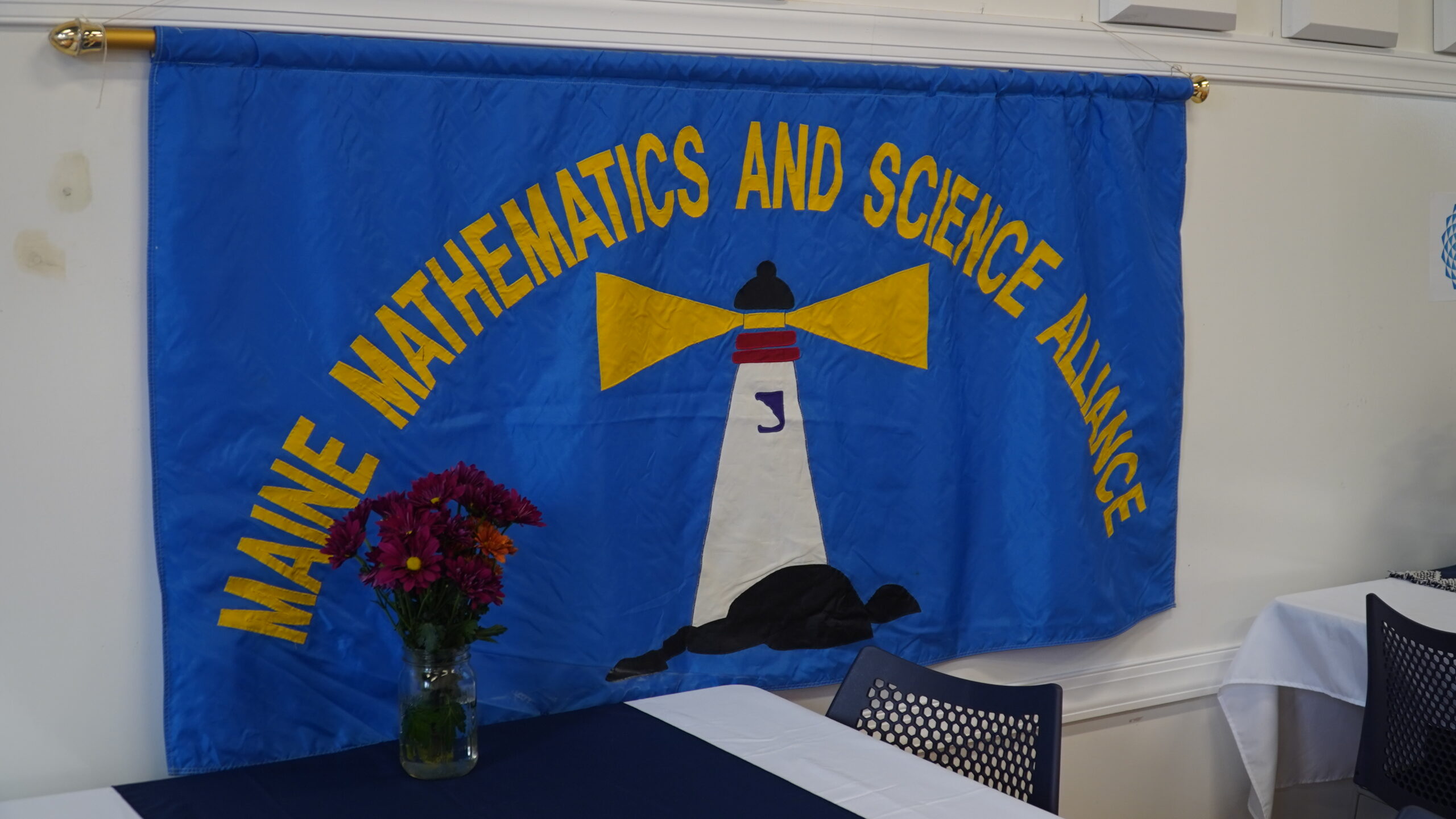 A Maine Mathematics and Science Alliance flag with the old lighthouse logo.