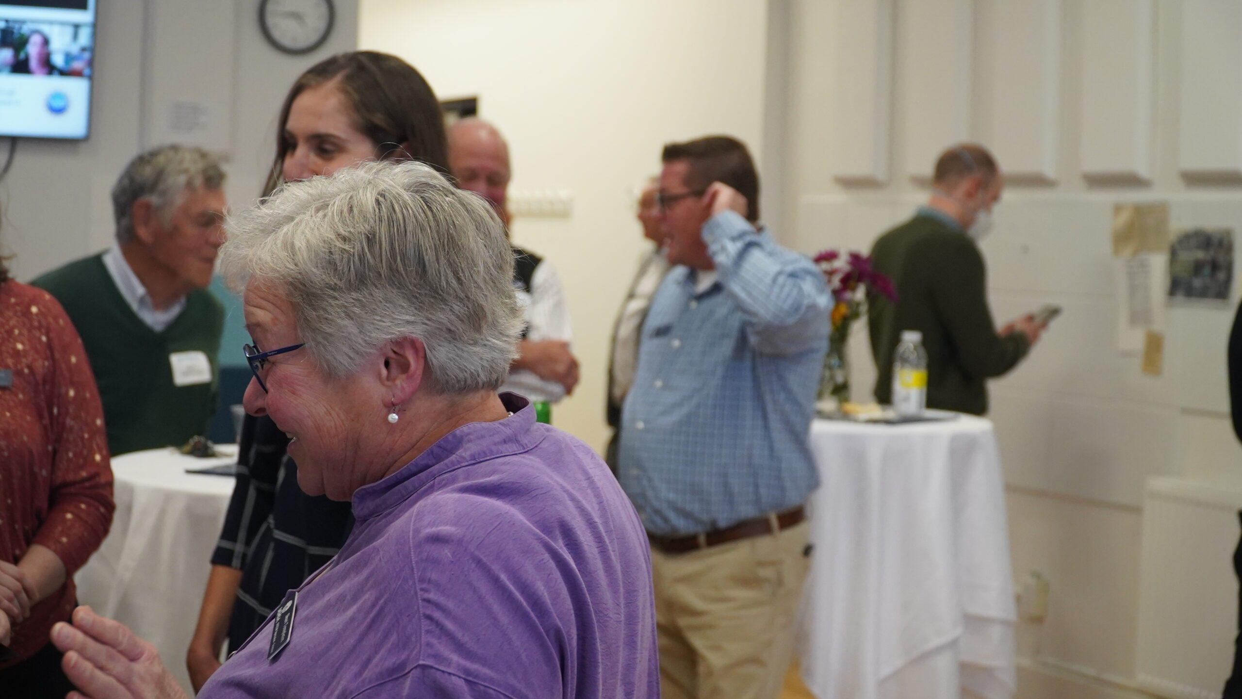 A group of attendees converse, while another views a timeline of documents hung on a wall in the background.