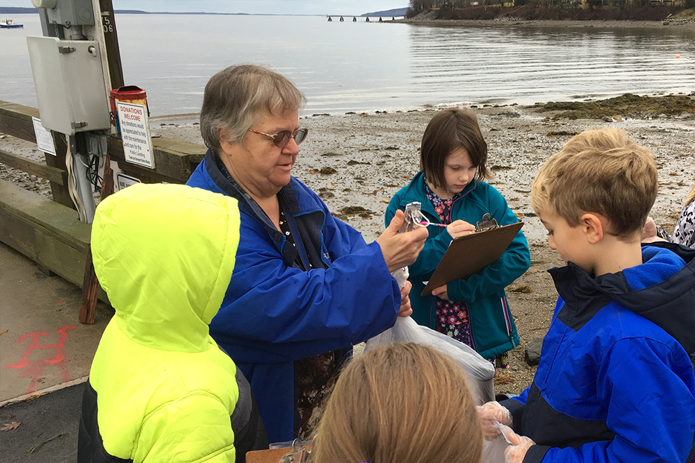 Students and their teacher participate in a citizen science project on a beach in Maine.
