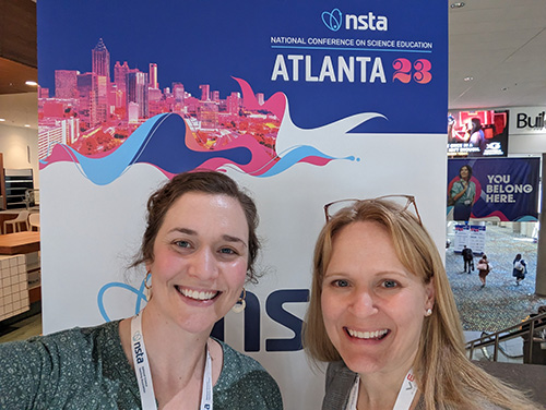 A photo of two women in front of a banner for the National Science Teachers Association conference banner in Atlanta, Georgia, in 2023.