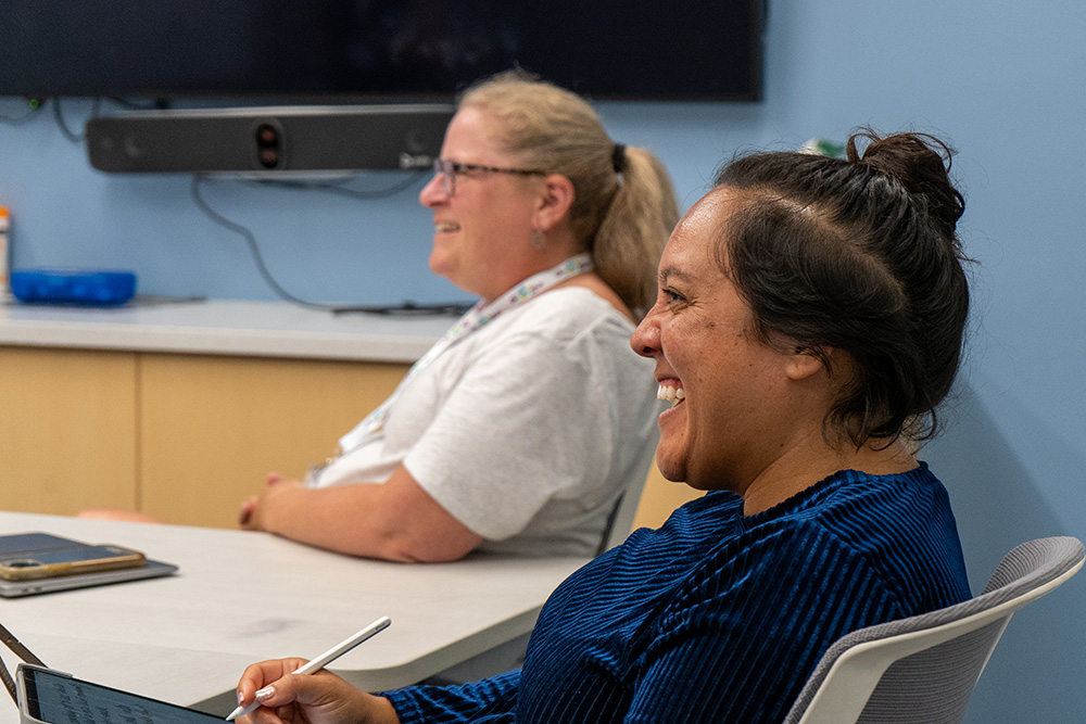 Two educators smile and look toward something off camera.