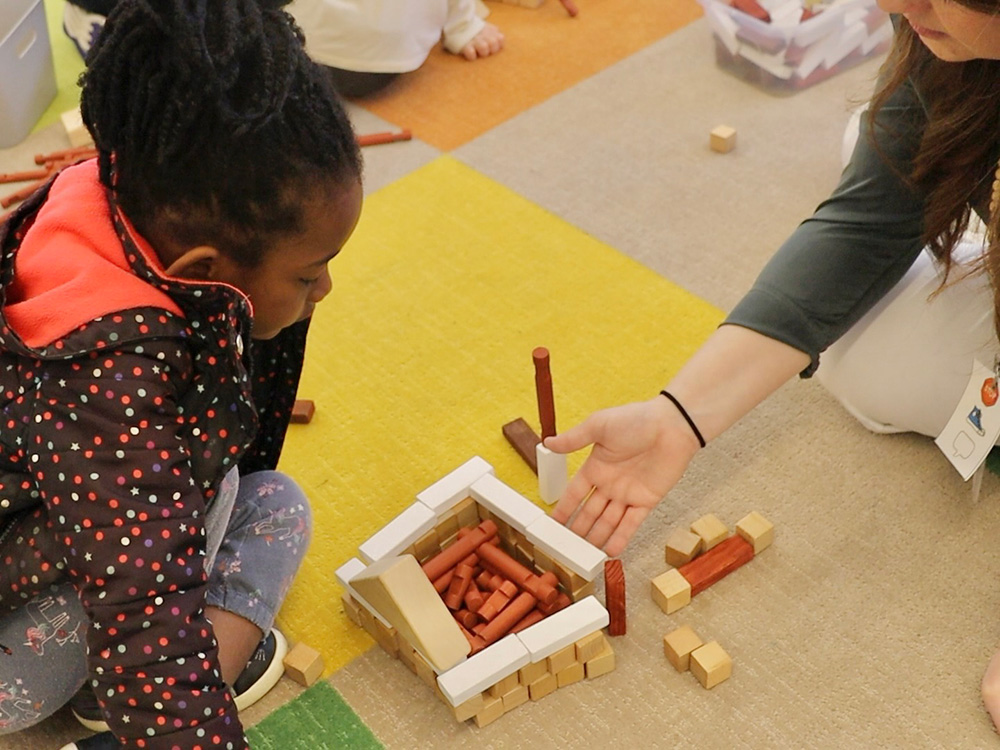 A kindergartener shares a model of an owl nest that she built out of blocks during free play.