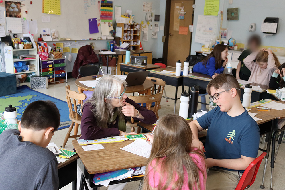 Becky Hallowell works with a group of students in an elementary school classroom.