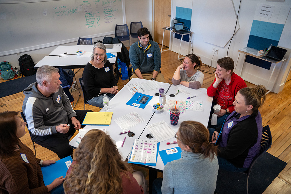 A group of educators sit around a table during an activity.