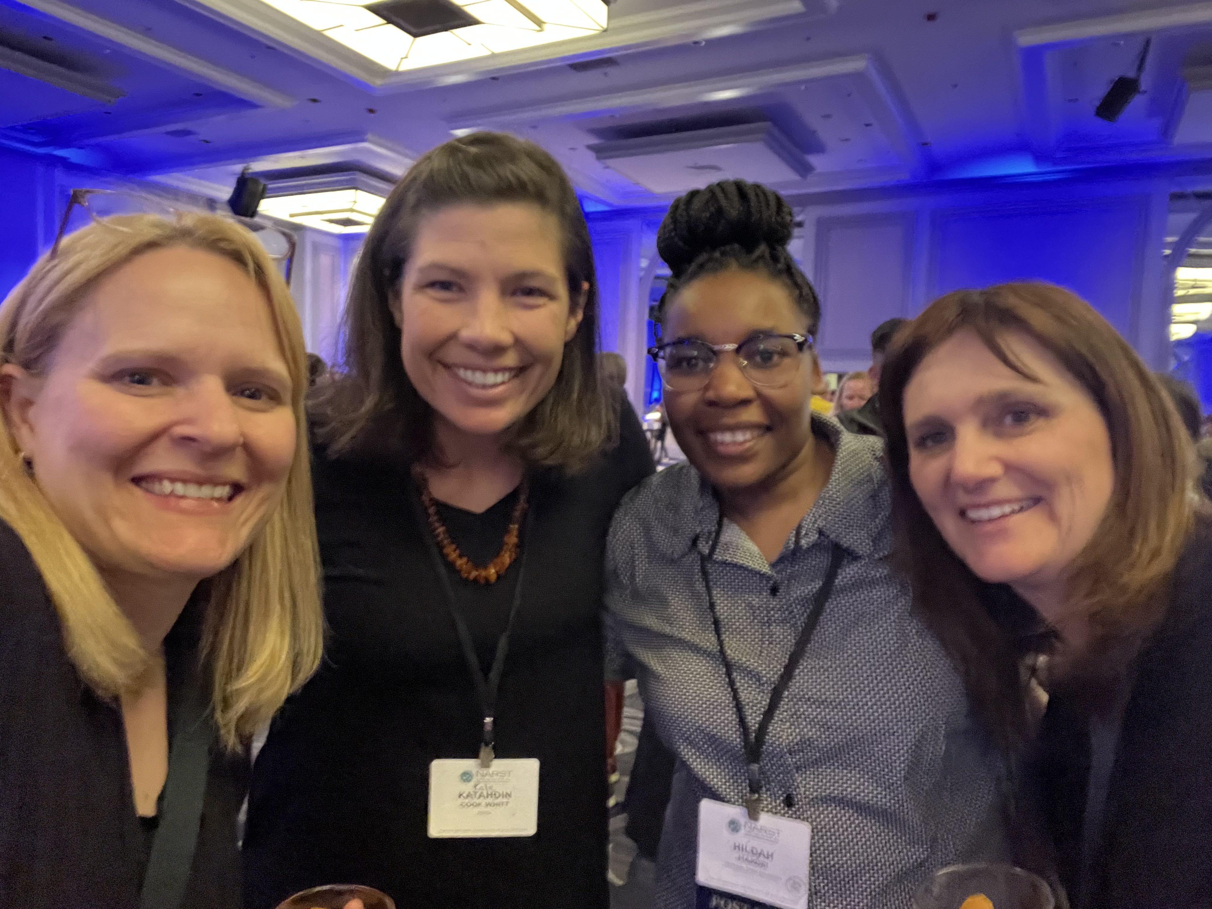 Four women pose for a photo at a conference.