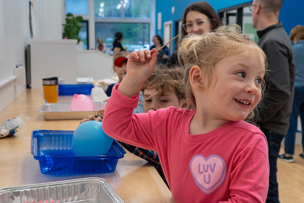 Children interact with stations set up with balloons and trays during the NSF 75 celebration in Maine.