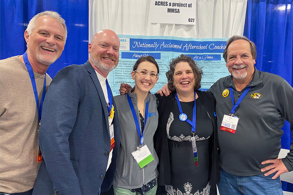A photo of ACRES staff and coaches at a conference in front of their table.
