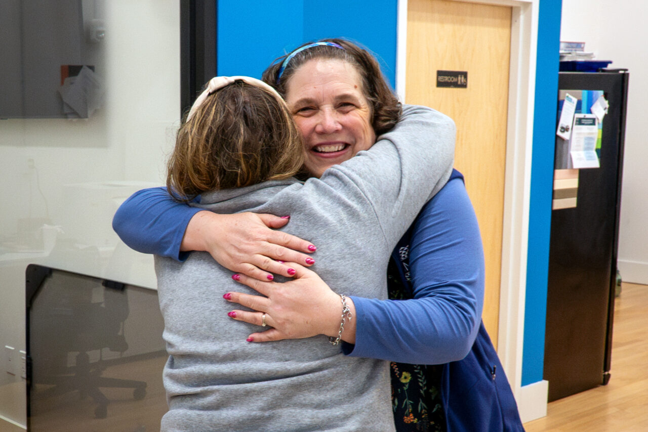 Perrin Chick hugs an attendee at an event at the MMSA offices.