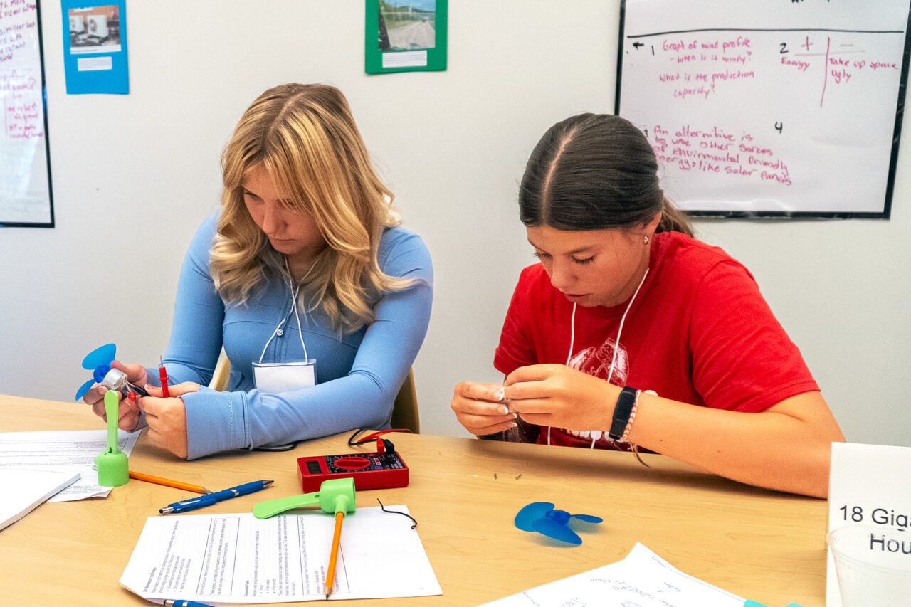 Two student participants in the Rural Energy Futures project work with a digital multimeter and electric fans.