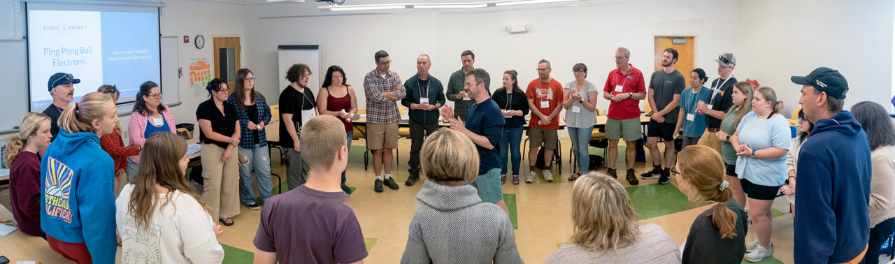 Rural Energy Futures project participants, including staff, students, and energy sector mentors, stand in a circle for an activity.