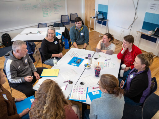 Participants in a professional learning activity converse around a table.